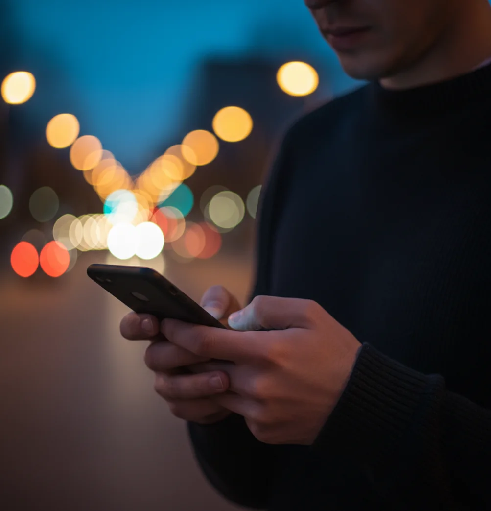 Phone photo with sharp subject and softly blurred city lights behind them