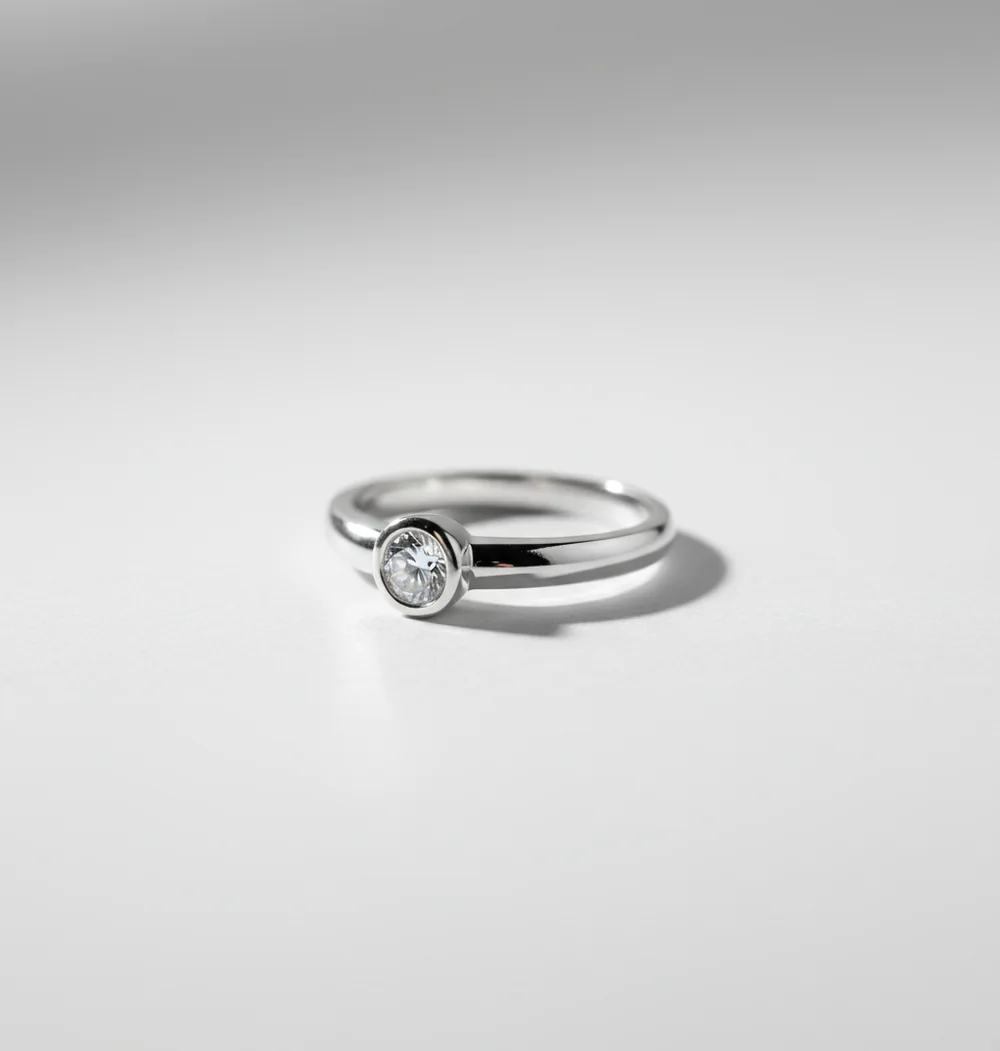 Silver ring on white backdrop with soft reflections, edited to look like a studio product photo